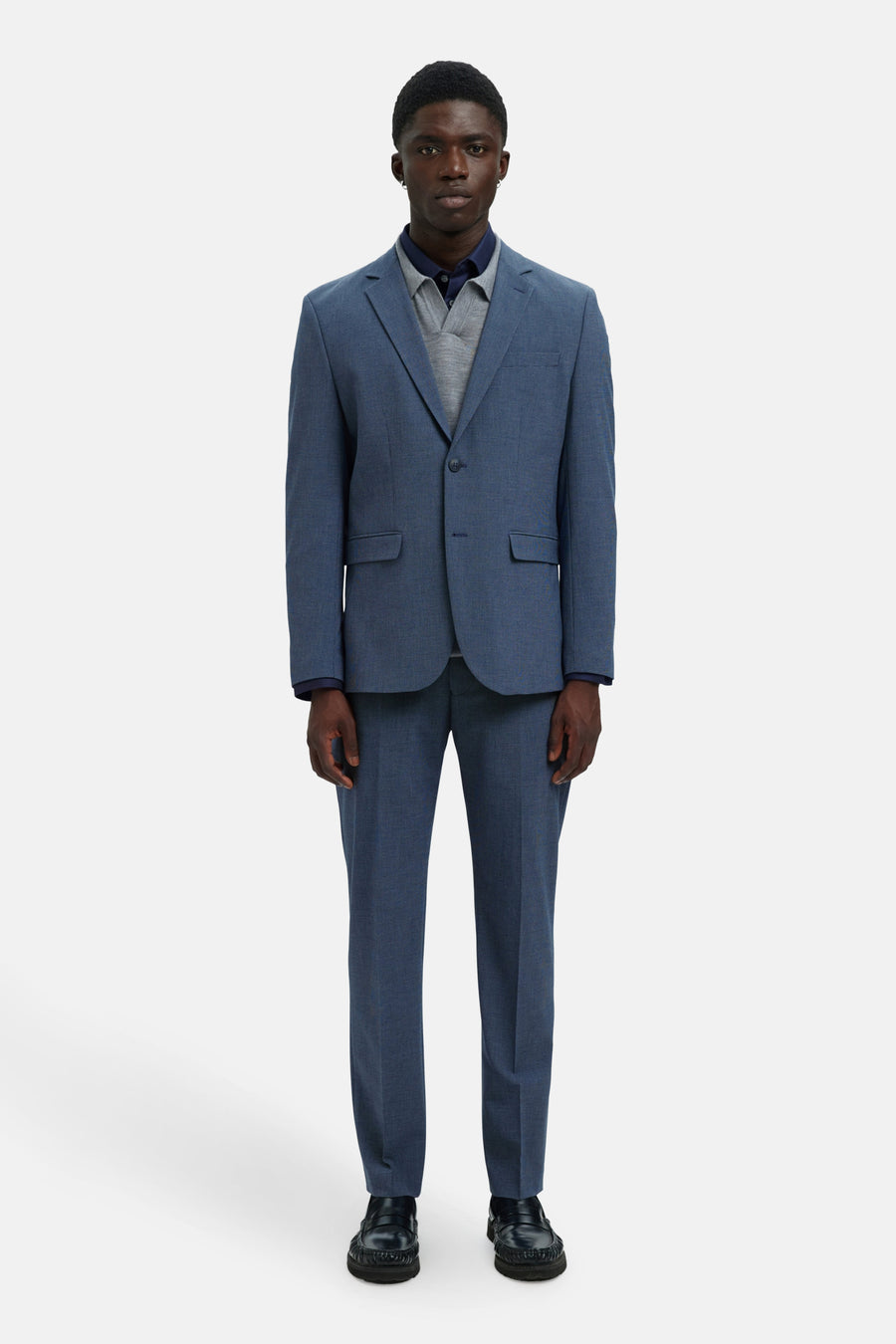 Blazer bleu par SELECTED, porté avec un polo bleu marine et un pull gris.
