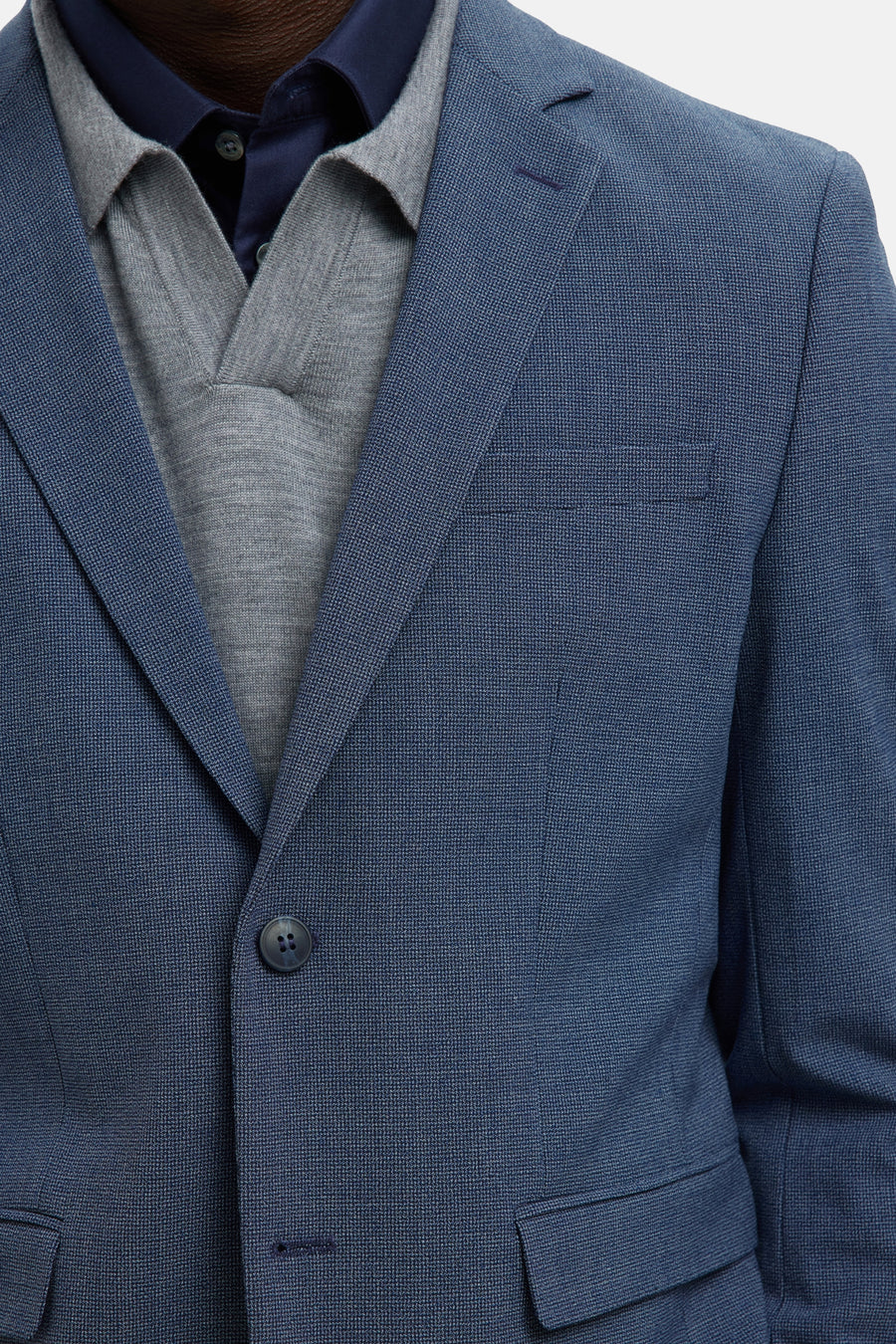 Blazer bleu SELECTED, avec une texture discrète, porté sur un polo gris et une chemise bleu marine.