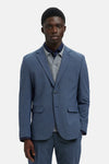 Blazer bleu de SELECTED, porté sur une chemise bleu marine et un pull gris.