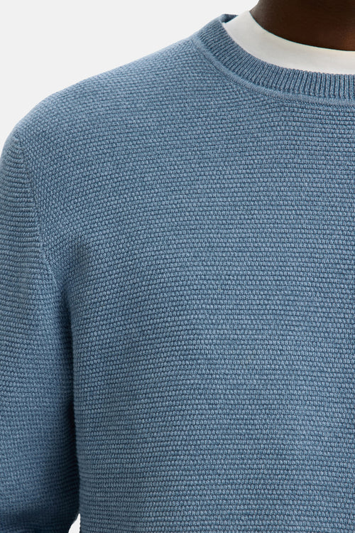 Ronde hals trui blauw van SELECTED, in een geweven textuur, met een wit T-shirt zichtbaar bij de hals.
