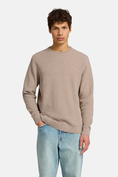 Ronde hals trui met textuur in bruin van SELECTED, gedragen met een lichtblauwe jeans en bruine schoenen.