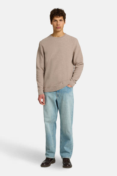Pull col rond brun en maille texturée de SELECTED, porté avec un jean bleu clair et des chaussures marron.