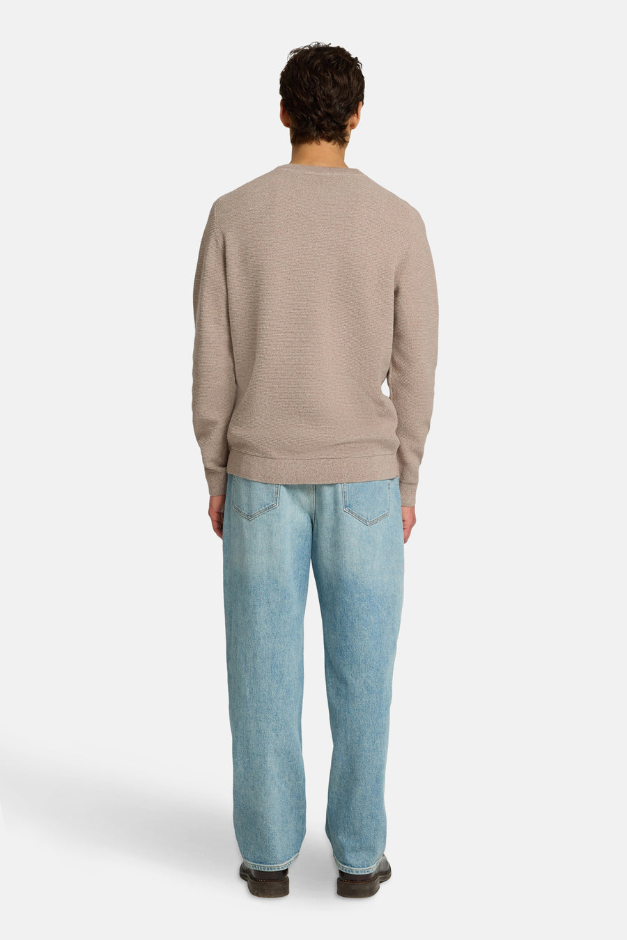 Ronde hals trui bruin van SELECTED, gedragen met een wijde blauwe jeans en bruine schoenen, achterzicht.