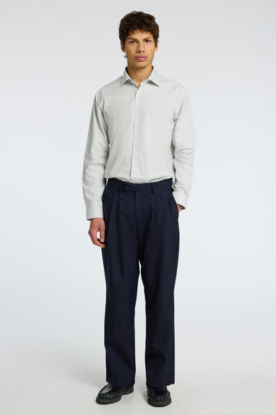 Chemise à manches longues verte de SELECTED, portée avec un pantalon bleu marine ample et des chaussures noires.