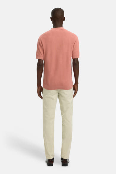 Polo rose de SELECTED avec une texture tricotée, porté avec un pantalon beige et des chaussures en cuir marron.