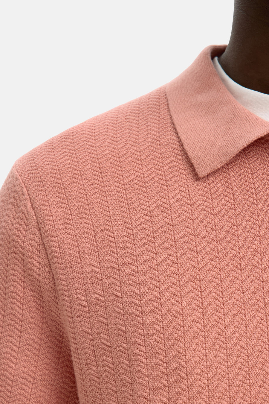 Polo rose SELECTED, à texture en maille et col classique, porté sur un t-shirt blanc.