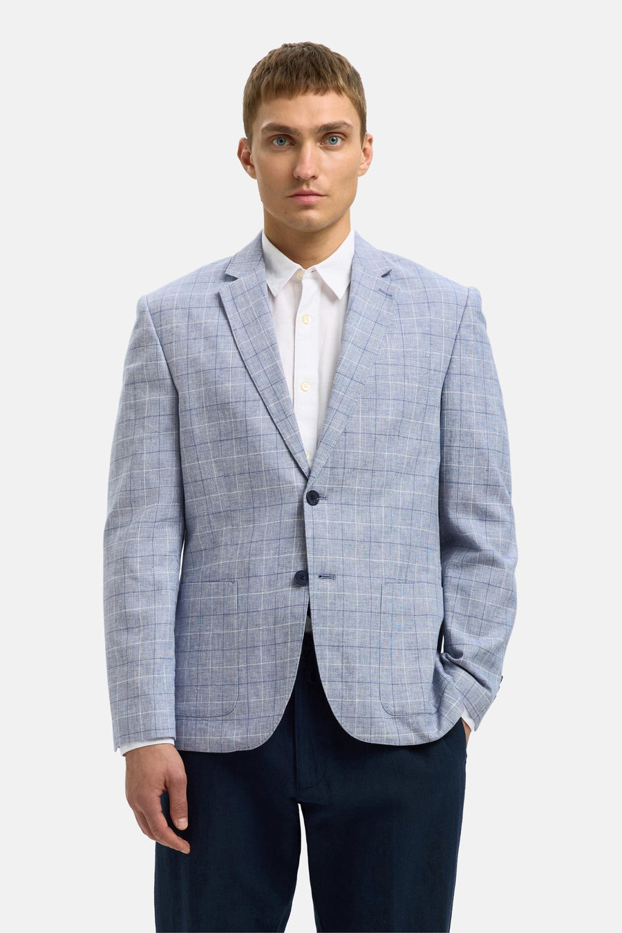 Blauwe blazer van SELECTED met ruitpatroon gedragen over een wit overhemd en een marineblauwe broek.