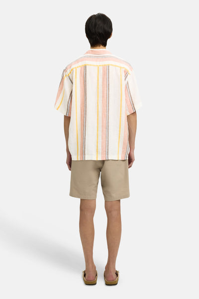 Chemise à manches courtes multicolore de SELECTED, rayée orange, jaune et marron, portée de dos avec un short beige et des sandales.