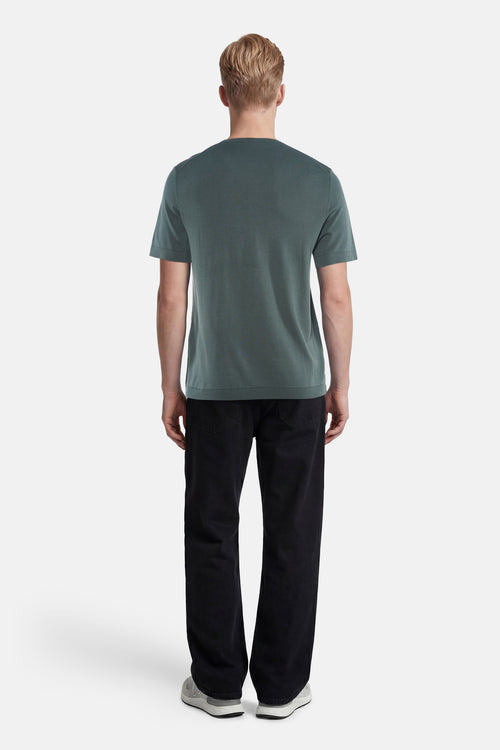 Pull col O vert en maille fine de SELECTED, porté de dos par un homme en jean noir et baskets.