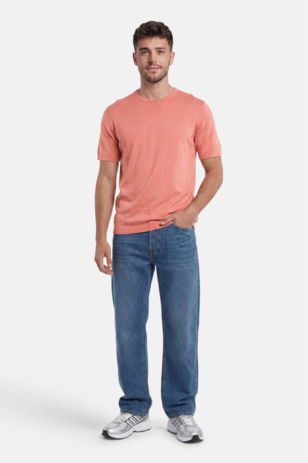 Pull col O rose de SELECTED à manches courtes, en tricot fin, porté par un homme avec un jean bleu et des baskets argentées.
