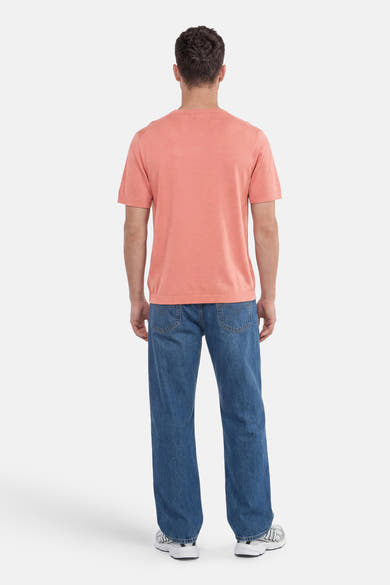 Pull rose de SELECTED à manches courtes, porté de dos avec un jean bleu et des baskets.