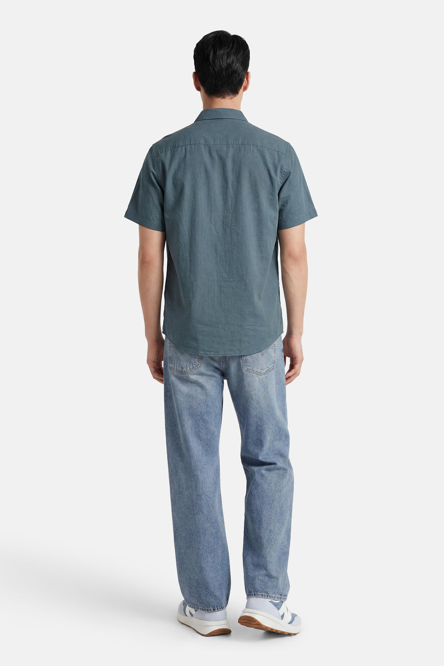 Chemise à manches courtes vert foncé de SELECTED, portée de dos par un homme avec un jean et des baskets.