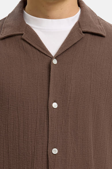 Bruin overhemd van SELECTED met wafeltextuur, met cubaanse kraag en witte knopen, gedragen over een wit T-shirt.