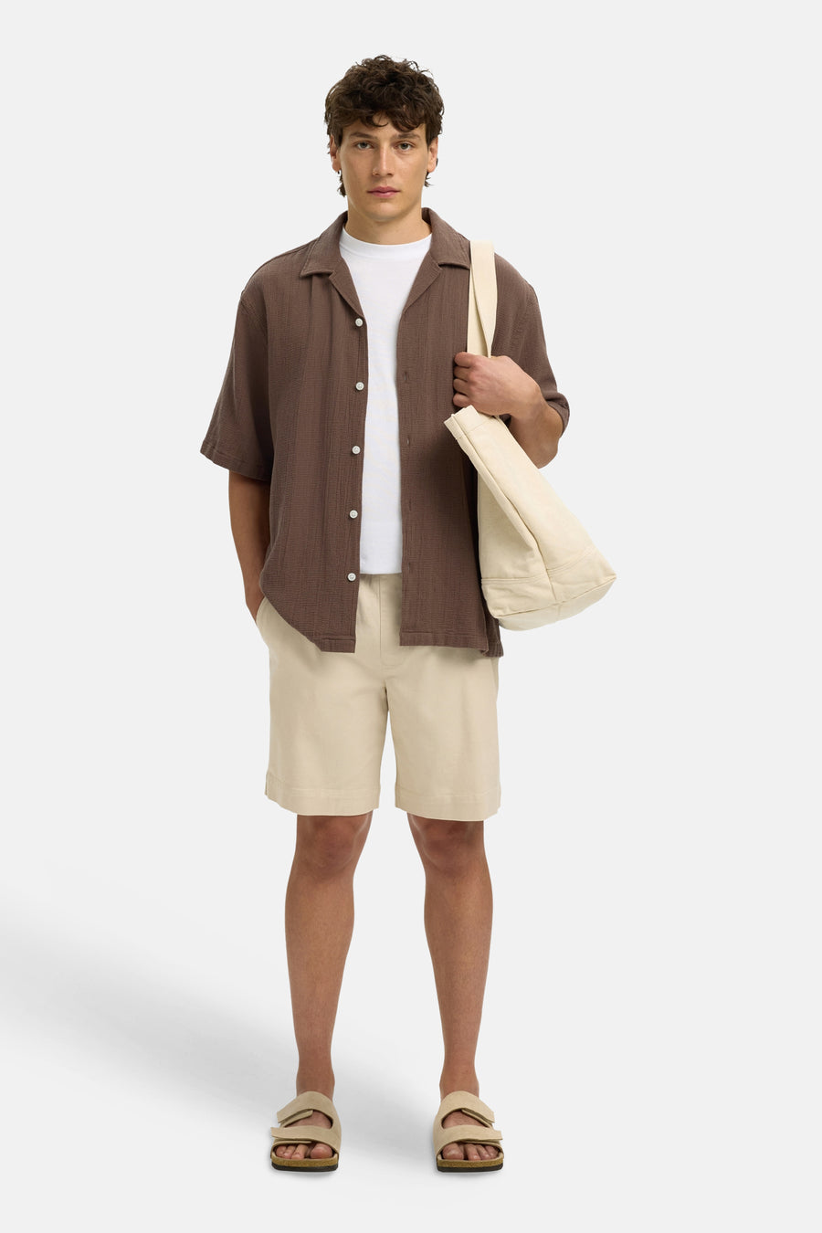 Bruin, getextureerd overhemd met korte mouwen van het merk SELECTED, gedragen open over een wit T-shirt met witte knopen.