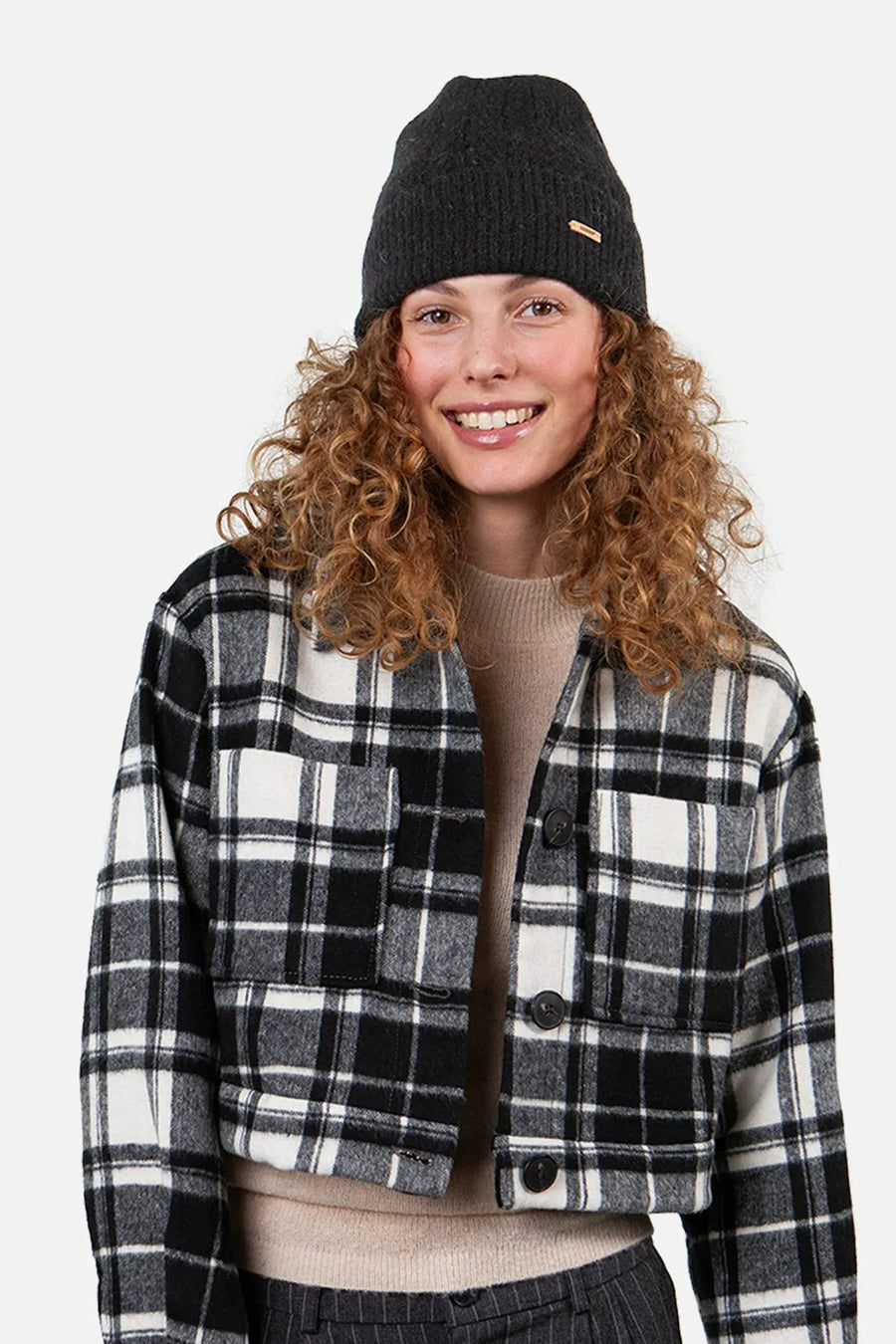 Bonnet noir de Barts, avec petite étiquette logo sur le côté, porté avec une veste à carreaux.