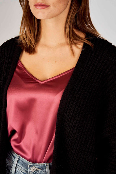 Zwarte Terra di Siena bodywarmer over een roze satijnen hemdje en een spijkerbroek.