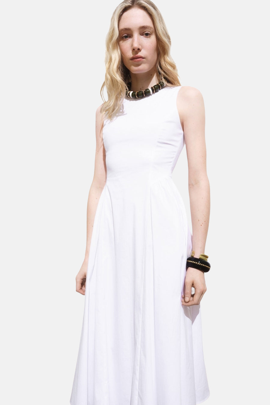 Witte jurk van MANGO, uitlopende pasvorm, met parelketting en zwart-gouden armband.