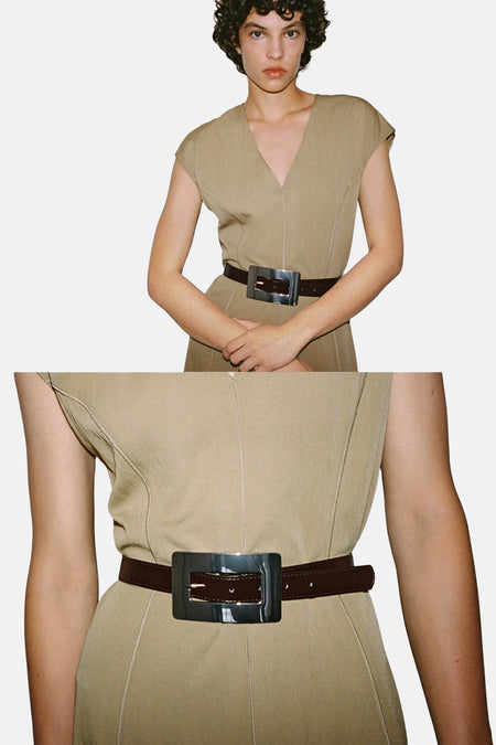 Bruine riem van MANGO, met een grote vierkante zilverkleurige metalen gesp, gedragen met een beige jurk.