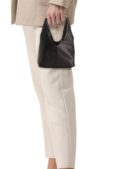 Zwarte leren handtas van MANGO, gedragen met een beige jas en gebroken witte broek.