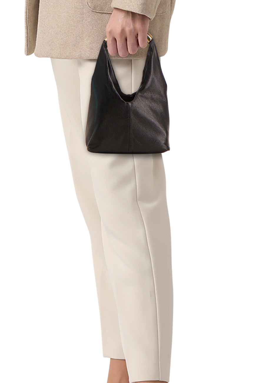 Zwarte leren handtas van MANGO, gedragen met een beige jas en gebroken witte broek.