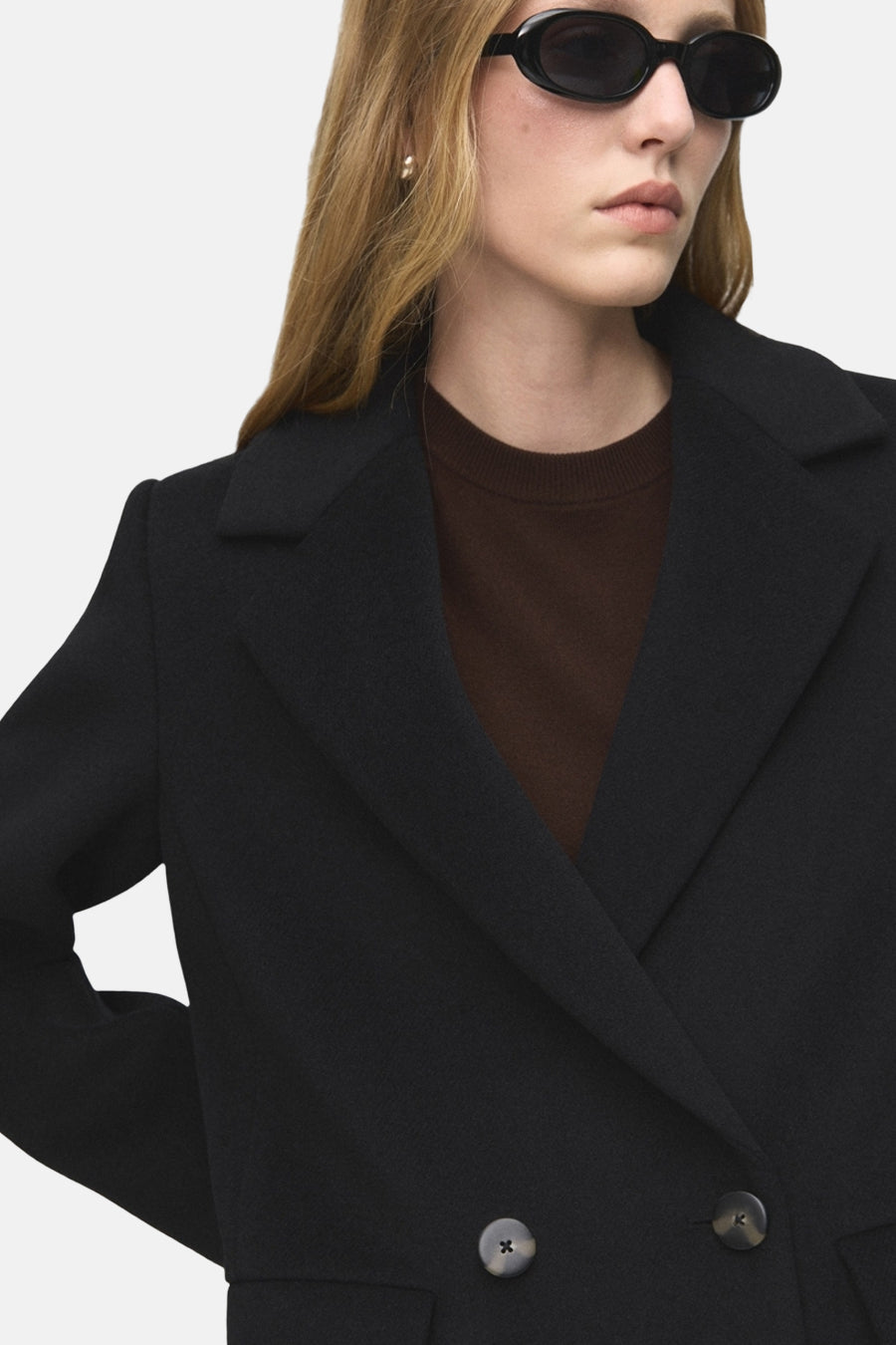 Veste longue noire de MANGO, avec un col à revers et une coupe croisée.