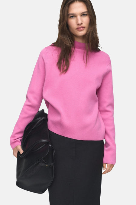 Roze coltrui van MANGO, gedragen met een wijde zwarte broek en een zwarte tas.