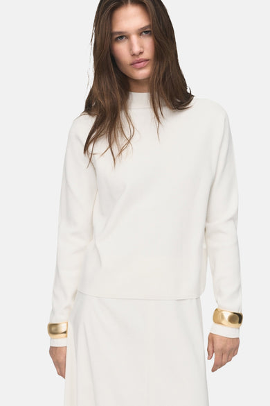 Witte rondehals trui van MANGO, gedragen met een lange witte ballonrok en gouden armbanden.