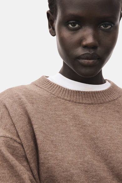 Pull à col rond brun de MANGO, porté sur un t-shirt blanc, en gros plan.
