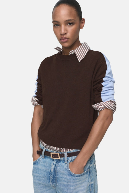Multikleuren rondehals trui van MANGO, opgerolde lange mouwen, gedragen met een lichtblauwe casual spijkerbroek.