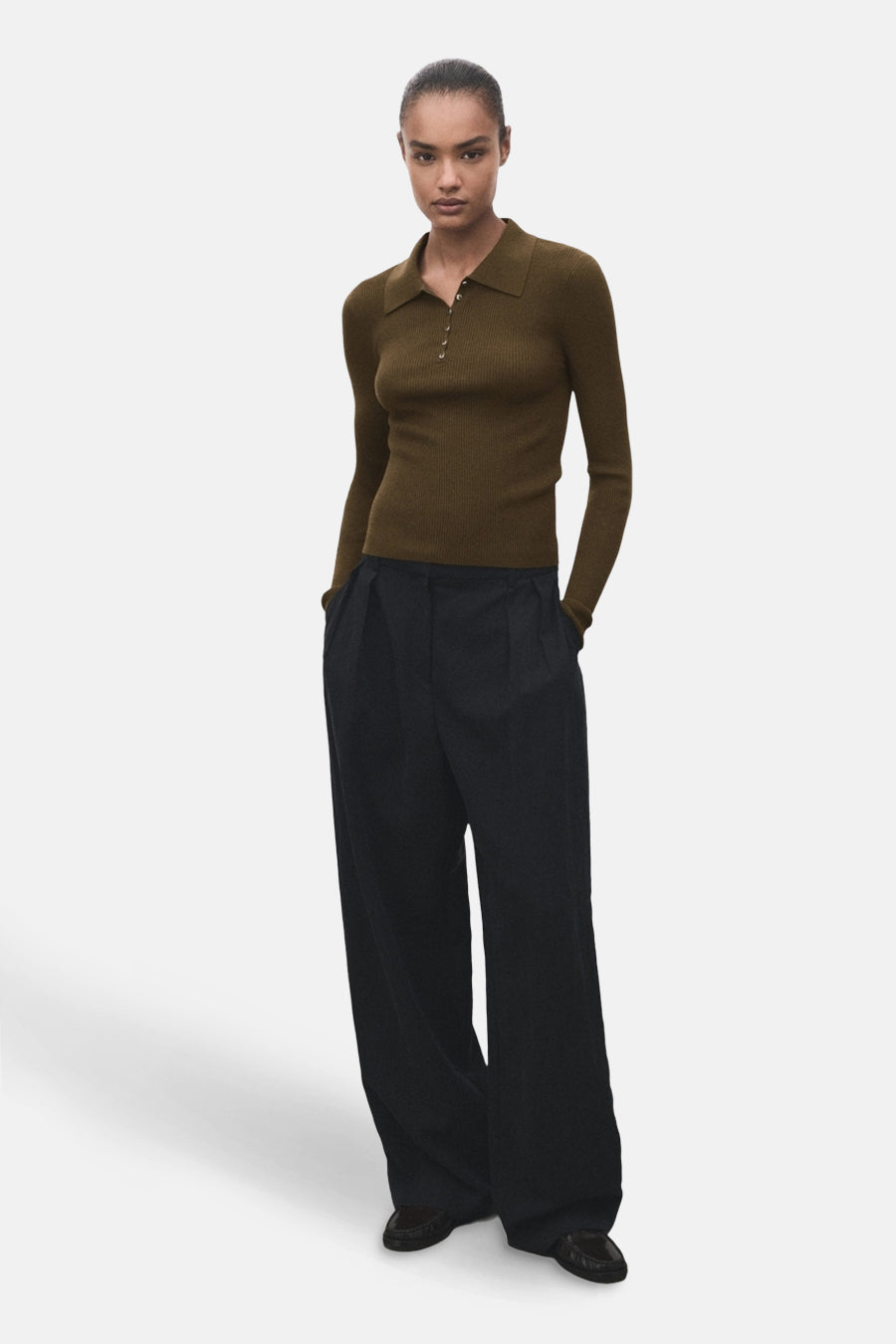 Pull à col rond kaki de MANGO, porté avec un pantalon ample noir.