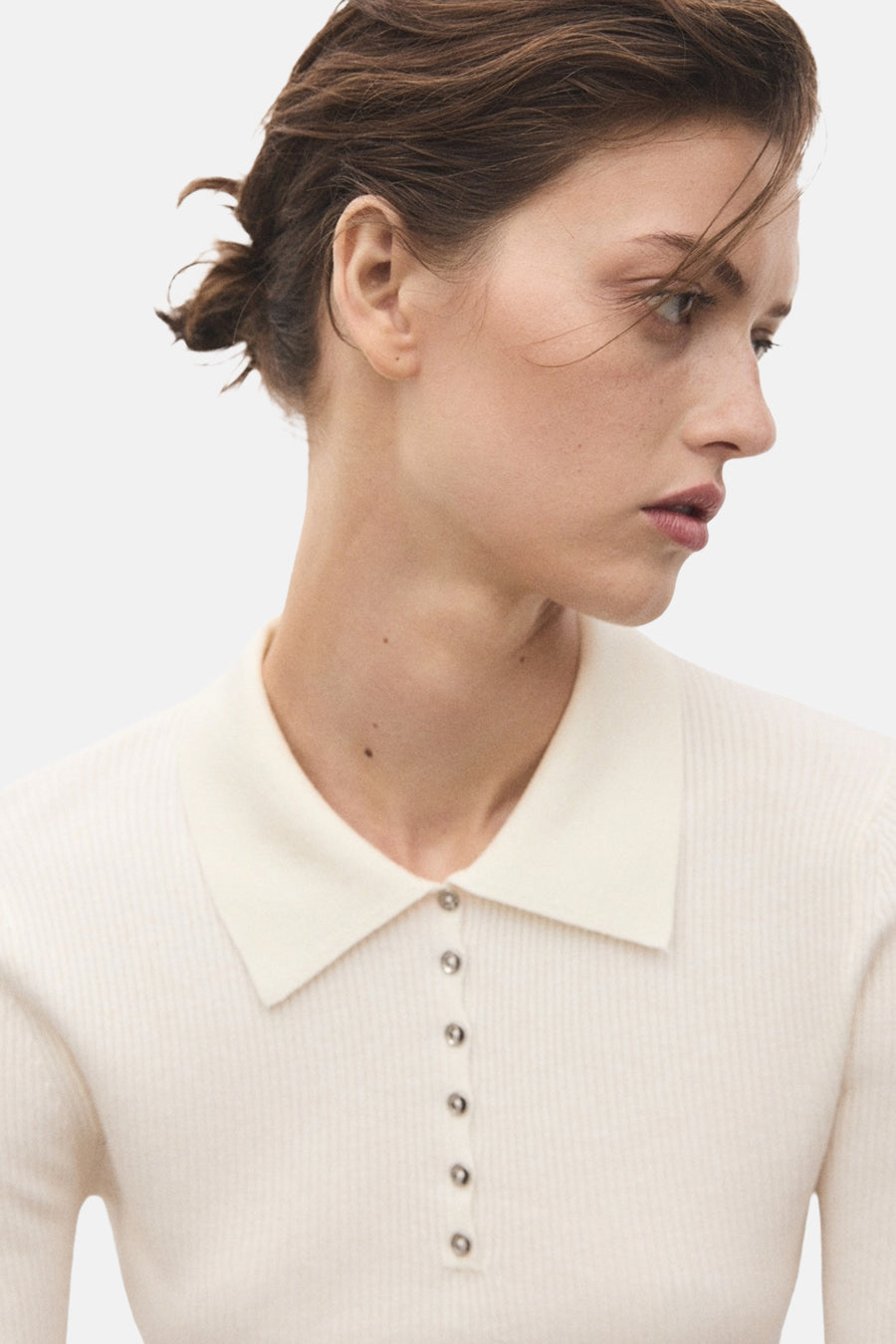 Pull à col rond beige de MANGO, à fines côtes et patte de boutonnage argentée.
