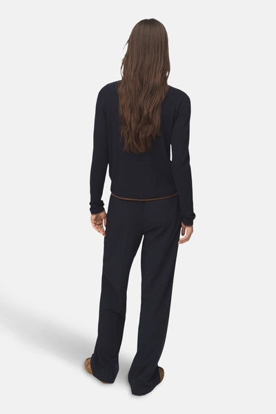 Pull à col rond bleu de MANGO, porté avec un pantalon et des chaussures marron.