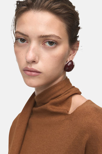 Pull à col rond brun de MANGO, avec un col montant et une épaule dénudée, porté par un mannequin.
