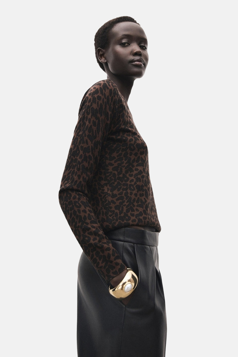 Pull à col rond marron par MANGO, avec imprimé léopard, porté avec une jupe noire et un bracelet doré.