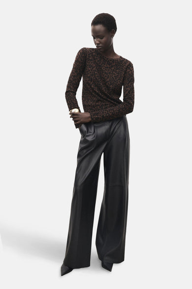 Pull à col rond brun de MANGO, avec motif léopard, porté avec un pantalon noir en similicuir.