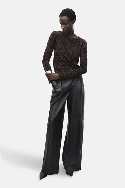 Pull à col rond brun de MANGO, avec motif léopard, porté avec un pantalon noir en similicuir.