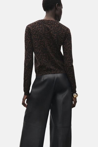 Pull à col rond marron de MANGO, avec motif animalier, porté avec un pantalon noir large.