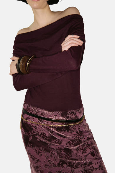 Pull à col rond bordeaux de MANGO avec des bracelets en bois et une jupe à motifs floraux.