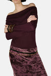 Pull à col rond bordeaux de MANGO avec des bracelets en bois et une jupe à motifs floraux.