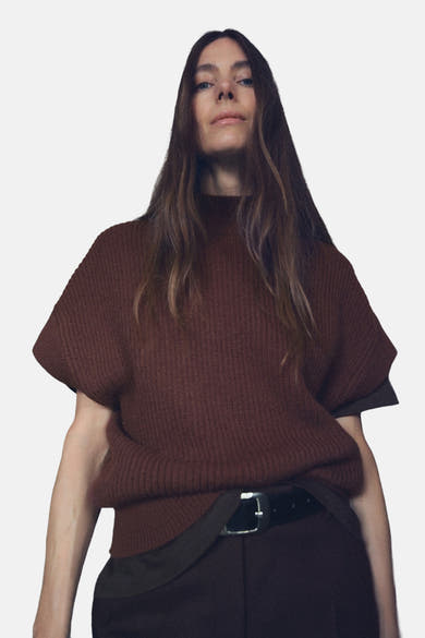 Débardeur marron de MANGO, porté avec une ceinture noire sur un pantalon marron.