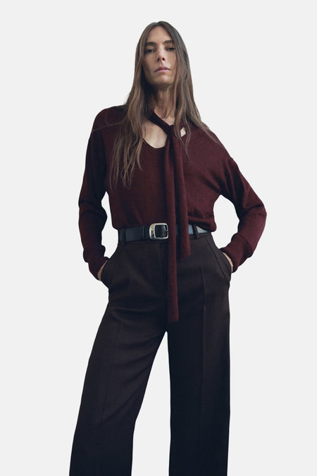 Bordeaux ronde hals trui van MANGO, gedragen met een broek met hoge taille en een zwarte riem.