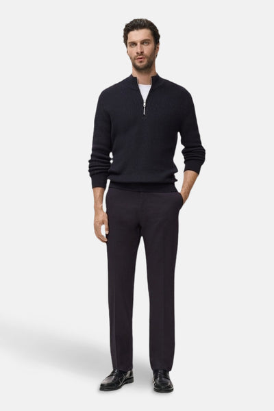 Blauwe coltrui van MANGO, getextureerd met een gedeeltelijke ritssluiting, gedragen met een wit T-shirt en een donkere broek.