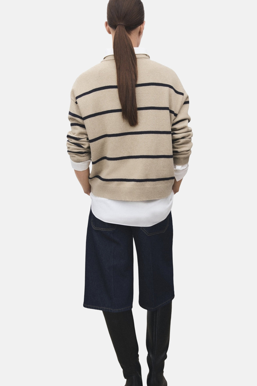 Pull à col rond beige à rayures by MANGO, porté avec un pantalon court en denim et des bottes noires.