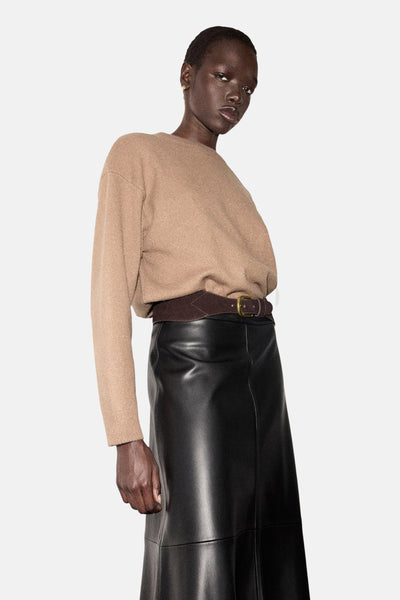 Pull à col rond marron by MANGO, porté avec une ceinture marron et une jupe longue en cuir noir.