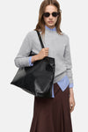 Pull à col rond gris de MANGO, porté avec une chemise rayée bleue et une jupe marron.