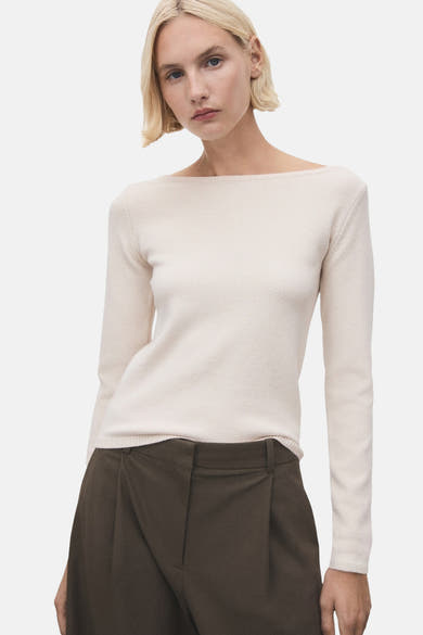 Pull à col rond écru de MANGO, porté avec un pantalon ample plissé marron.