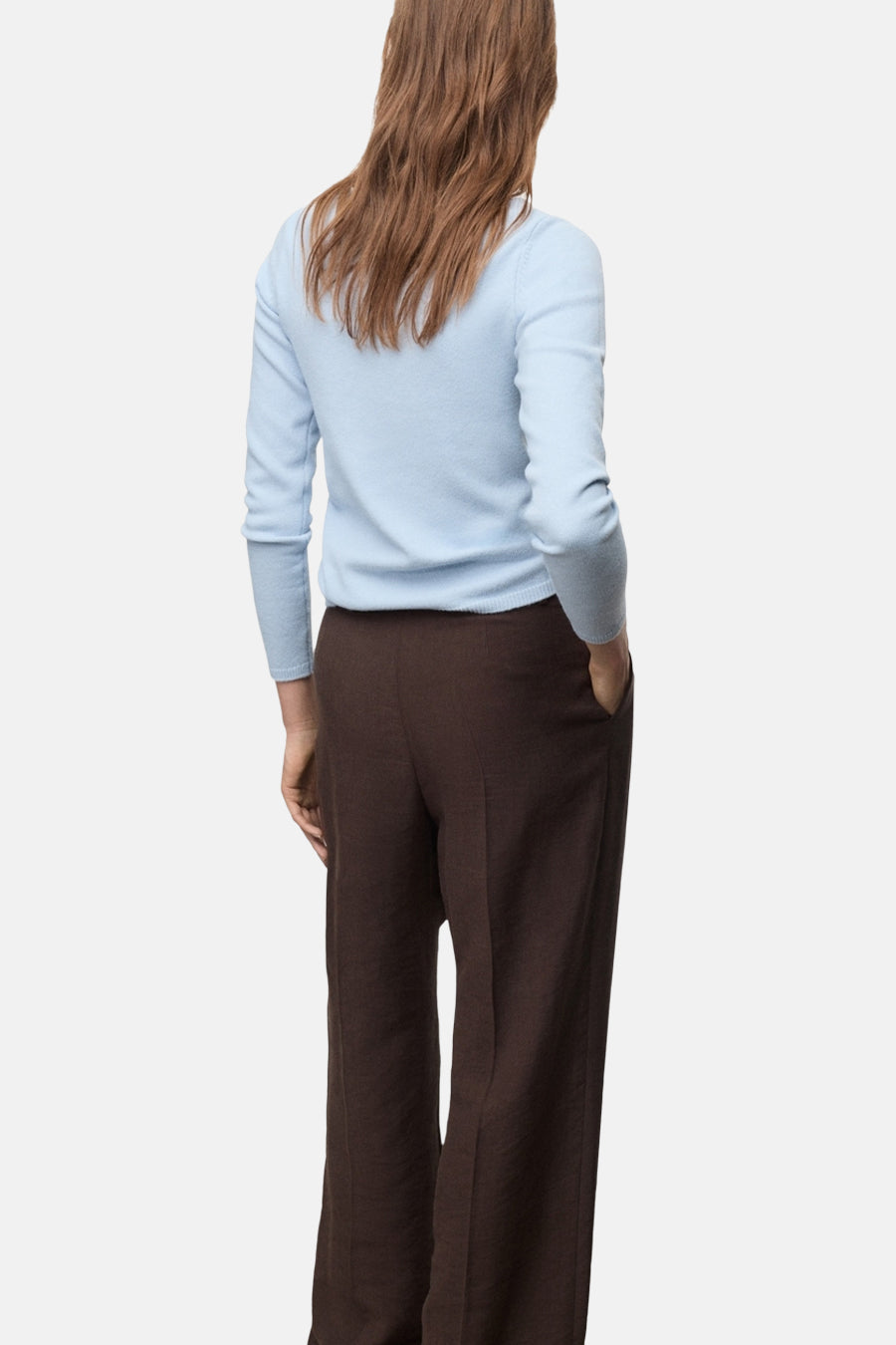 Pull à col rond bleu de MANGO, porté avec un pantalon marron à jambes larges, vue de dos.