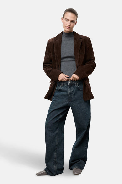 Pull à col rond gris de MANGO, porté avec un blazer en daim marron et un jean ample.