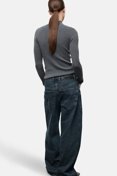 Pull à col rond gris de MANGO, porté avec un pantalon ample en denim, vue de dos.