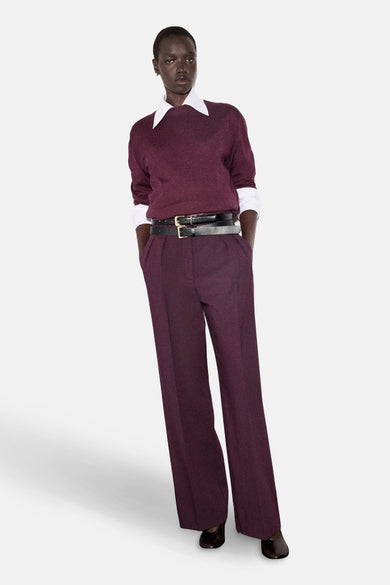 Pull à col rond bordeaux de MANGO, porté sur une chemise blanche, avec une double ceinture noire.